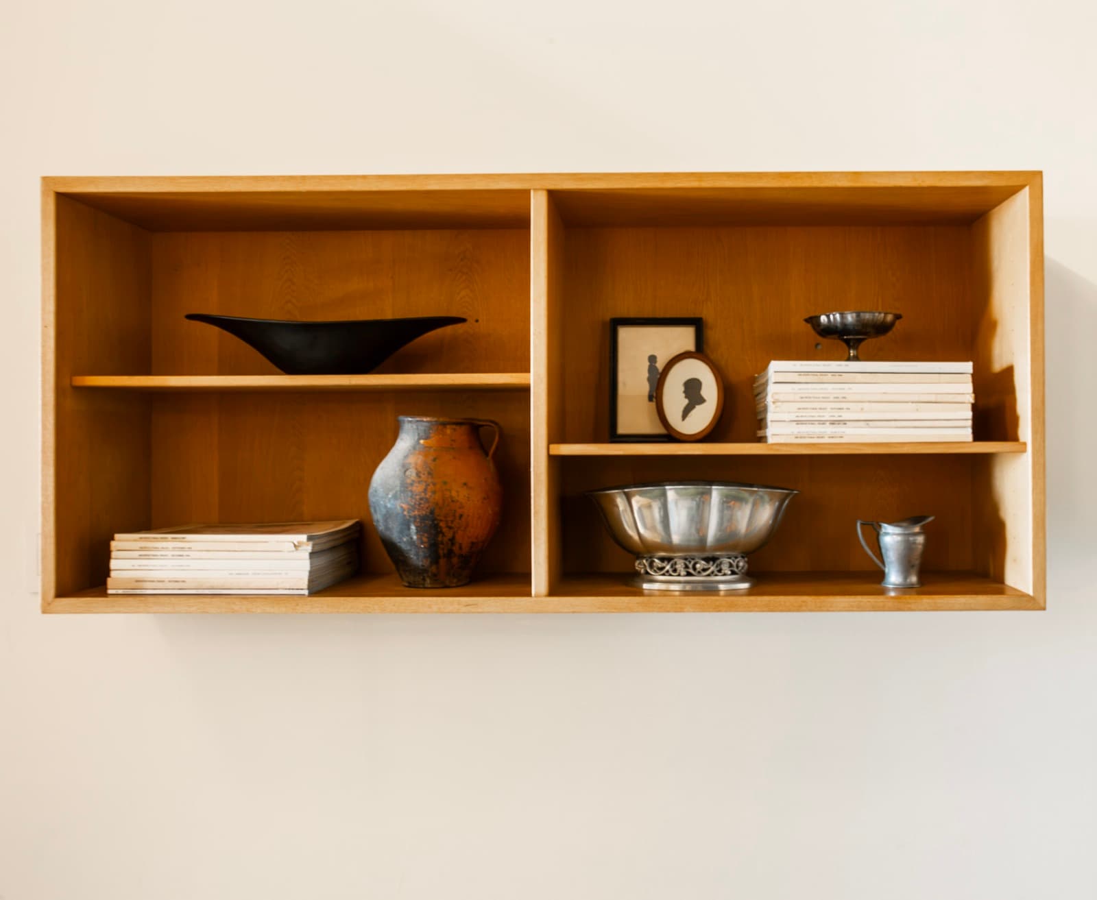 Oak wall shelf styled with ceramics, silver bowls, and vintage magazines